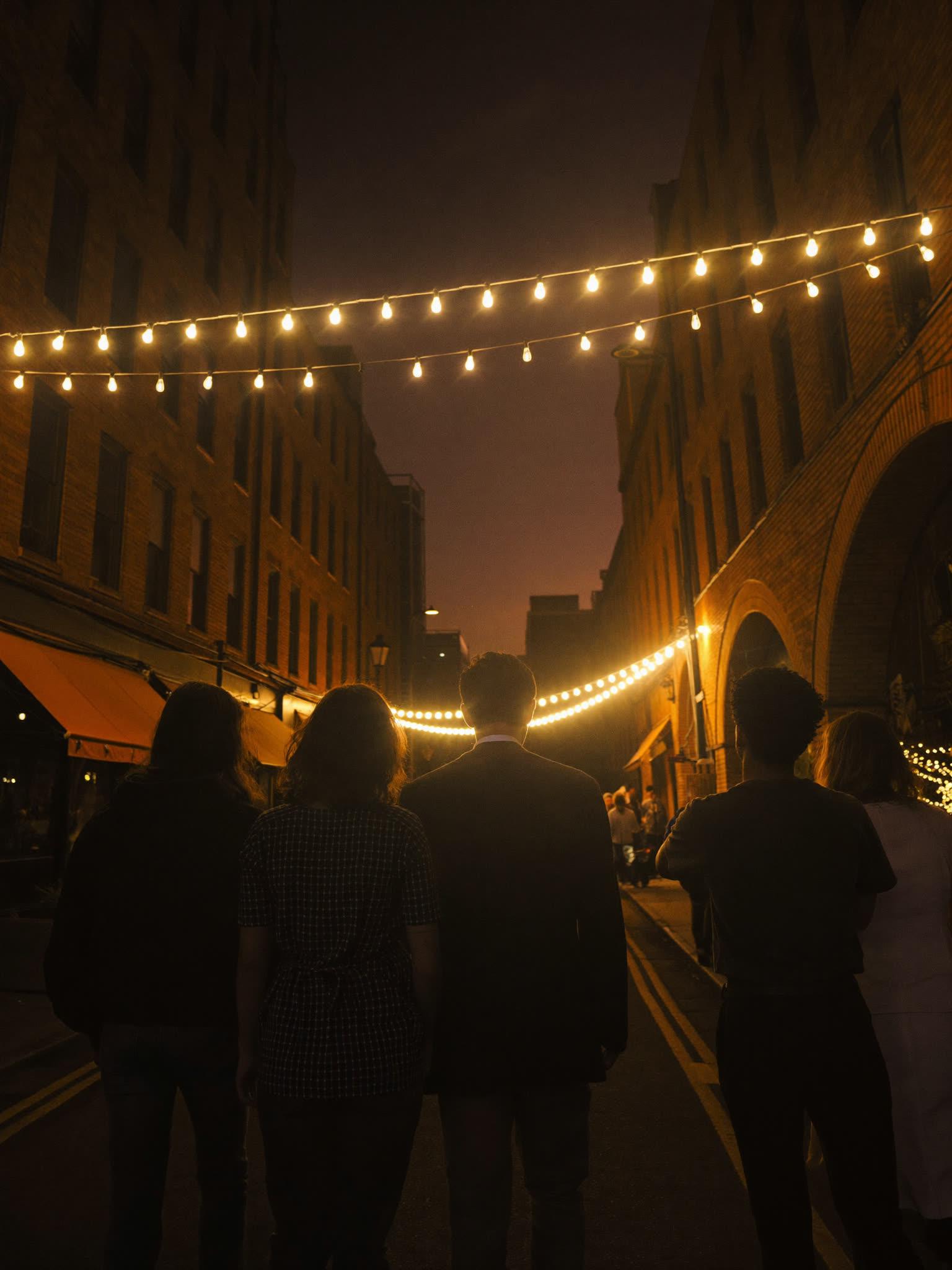 Friends walking together toward a glowing venue entrance at night