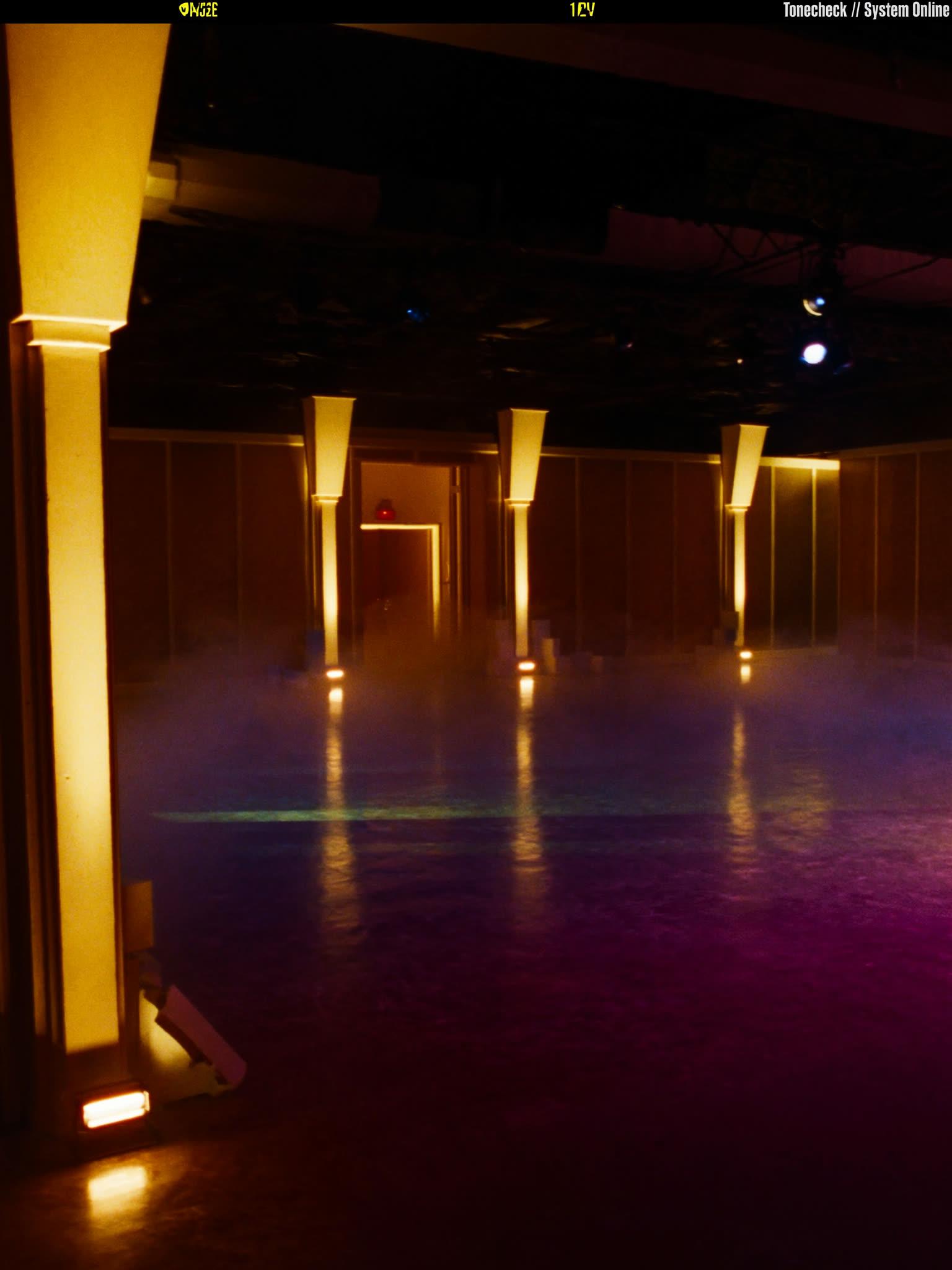 An empty venue interior lit with dramatic gold uplighting before doors